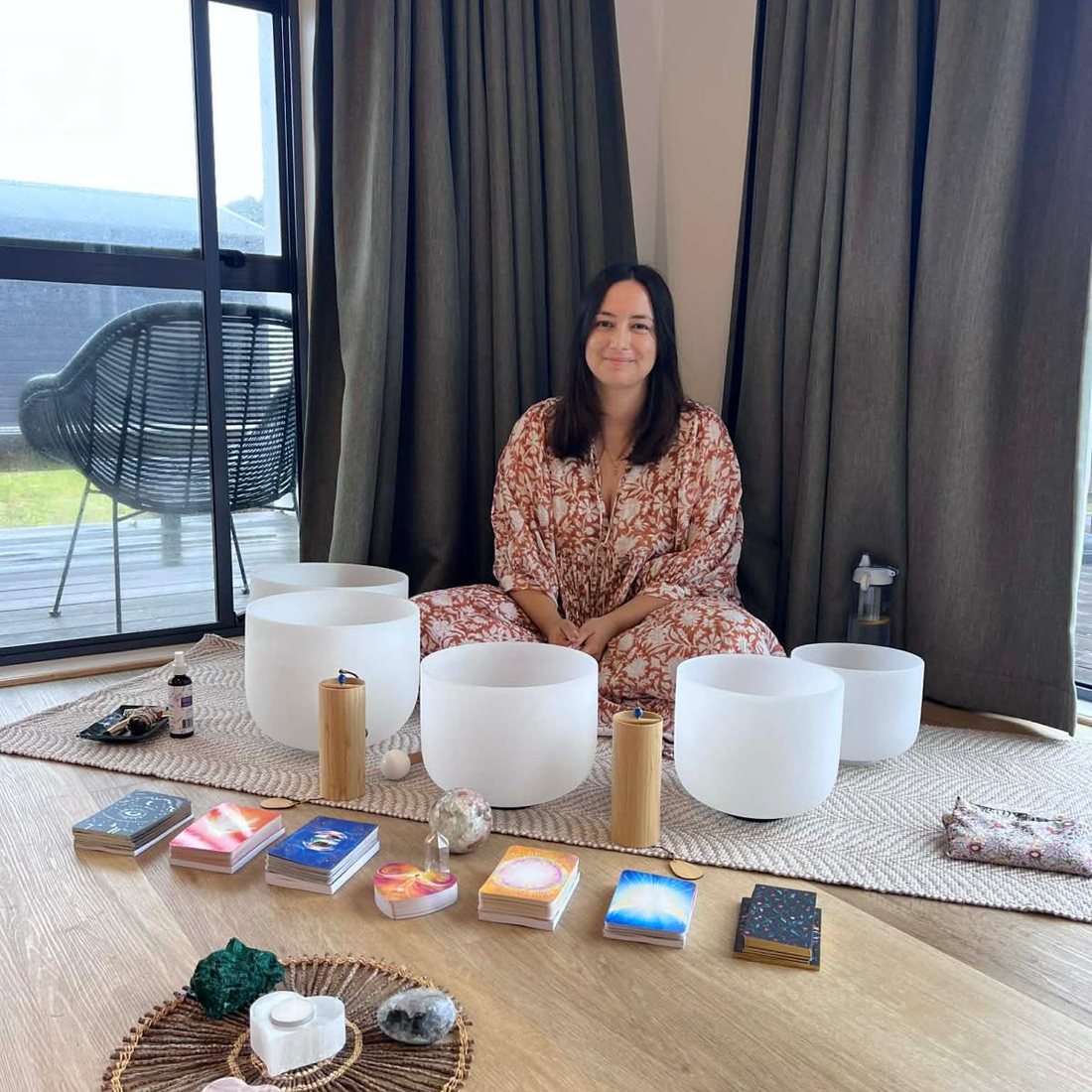 Sam seated in her home studio among crystal singing bowls and oracle card decks